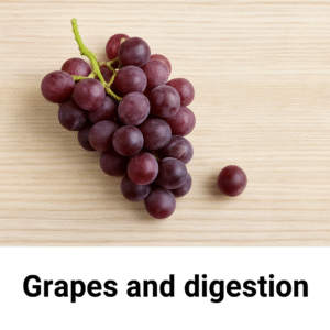 A bunch of purple-red grapes with a single grape on a light wooden surface