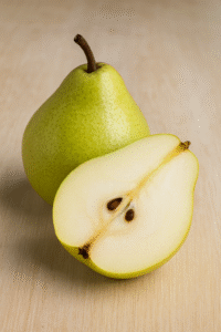 A whole pear and a halved pear on a light wooden surface